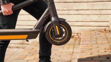 Close up of young men carries electrical kick scooter in hand photo