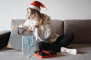 Beauty girl opening present gifts sitting on sofa at home photo