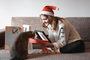 niña feliz con sombrero de santa abriendo caja de regalo de navidad foto