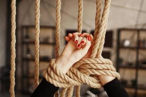 Tied with a rope female hands with red nails photo