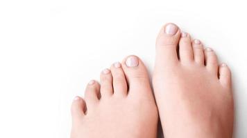 Woman feet with soft pink manicure isolated on white photo