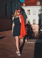 Pretty young Woman in red jacket on city street urban background photo