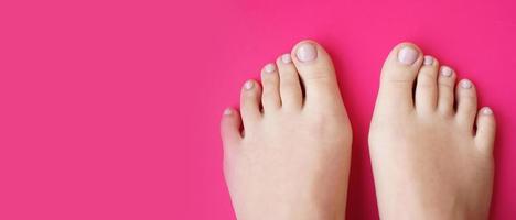 Young perfect groomed womans feet on pink background. Care about nails photo