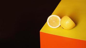 Limón amarillo fresco sobre fondo negro y naranja foto