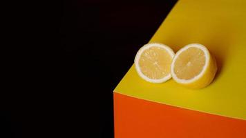 Fresh yellow lemon on black and orange background photo