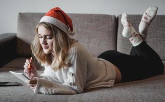 Portrait of pretty girl at Christmas writes plans for the new year photo