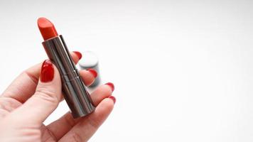 Woman Hand With Red Nails Holding Red Lipstick photo