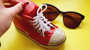 Moneybox in the form of sneakers. Sunglasses on a yellow background photo