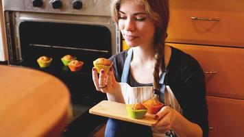 Hermosa mujer rubia mostrando muffins en una cocina foto