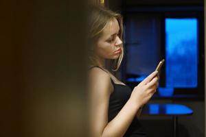 European young woman holds modern phone, dressed in casual clothes photo