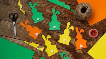 Easter bunnies made of paper on a wooden background. Create a decor photo