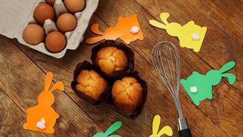 Homemade muffin with paper rabbits. Muffin and eggs on a wooden photo