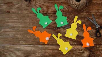 Easter bunnies made of paper on a wooden background. Create a decor photo