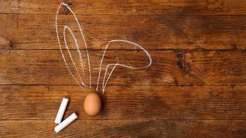 Egg on a wooden background. Chalk-drawn ears photo