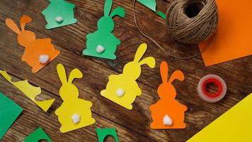 Easter bunnies made of paper on a wooden background. Create a decor photo