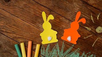 Two Easter bunnies made of paper. Drawn with colored chalk grass photo