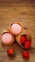 helado de fresa en un cono de galleta. frutos rojos y bolas de helado foto