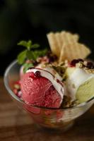 Strawberry and pistachio gelato ice cream sundae dessert in bowl on wooden table