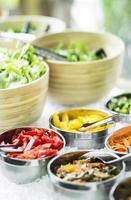 Bowls of mixed fresh organic red peppers and vegetables in modern salad bar display photo