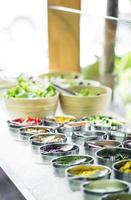 Bowls of mixed fresh organic red peppers and vegetables in modern salad bar display photo