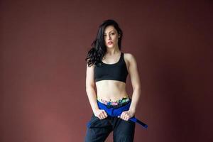 Beautiful athletic woman with blue belt on the wall background photo