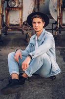 Man with hat sitting on skateboard on background old neglected building photo