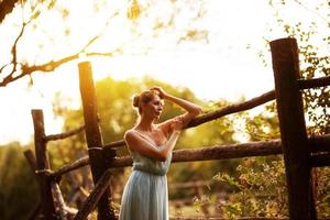 Young pensive woman stands near hedge photo