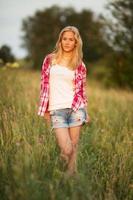 Beautiful girl standing among the grass of the field photo