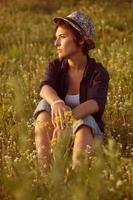 Woman in hat sitting among wildflowers photo