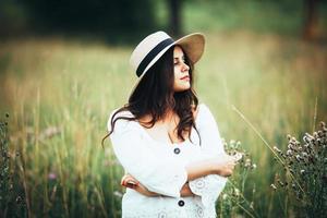 Bella mujer con un sombrero de paja entre la hierba del campo foto