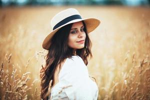 Bella mujer con sombrero de paja entre la hierba del campo foto