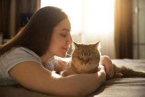 niña abrazando a su amado gato rojo. centrarse en el gato foto