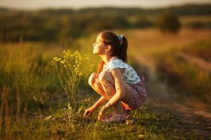 Girl inhales aroma of a wildflower photo