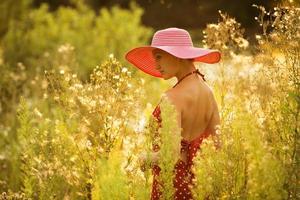 hermosa mujer camina entre altas flores silvestres foto
