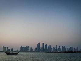 Doha city skyscrapers urban skyline view and dhow boat in Qatar photo