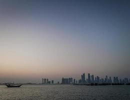 Doha city skyscrapers urban skyline view and dhow boat in Qatar photo