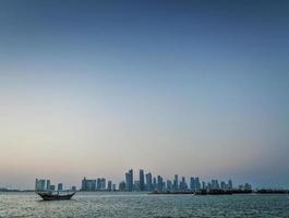 Doha city skyscrapers urban skyline view and dhow boat in Qatar photo