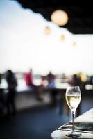 Glass of sparking champagne wine at modern outdoor bar at sunset photo