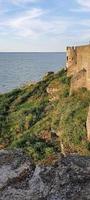 Ruined old fortress on the seashore. Blue sky. photo