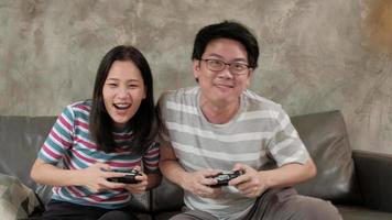 Asian man playing video games console with his girlfriend