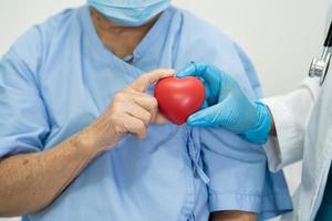 El doctor le da un corazón rojo al paciente asiático de la mujer mayor foto