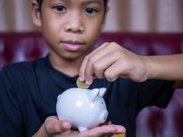 Boy saving money in a white pig piggy bank.Saving concept photo