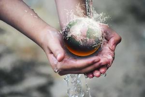Hand holding the smoldering globe under pouring water photo