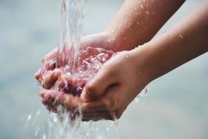 Hand catches water drops coming out of faucet photo