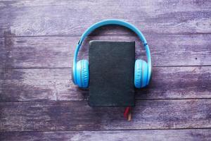 Audio book concept. Headphones and notepad on wooden background photo