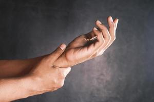 Man suffering pain in hand against black background photo