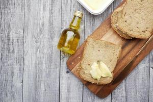 Slice of butter and whole meal bread on chopping board photo