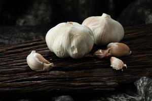 garlic cloves and bulb on vintage wood black cloth photo