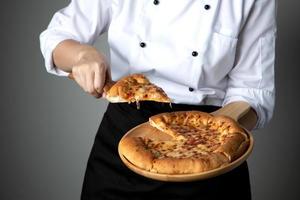 Sartén de pizza en la mano del chef con queso foto