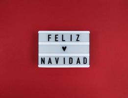 Light box with Feliz Navidad phrase, Spanish Merry Christmas on a red photo